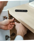 HIAKDOFT stainless steel concealed cabinet hinges installed on a wooden cabinet door; hands tightening with screwdriver.