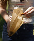 Person holding natural paper sandwich bags with greaseproof barrier, 48 count pack, unbleached eco friendly lunch bags outdoors
