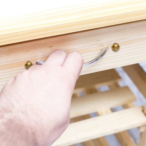 Close-up of hand using drawer pull with Top Shelf Brass Decorative Screws 24 Pack 15Mm on wooden furniture.