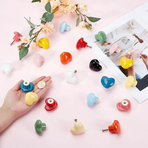 Heart Shaped Porcelain Cabinet Knobs Set 24 Pieces In 12 Colorways Ceramic Kitchen Dresser Knobs arranged on table with hand holding