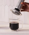 Using the All In One Coffee Press With Glass Chamber, Stainless Steel And Aluminum Build, French Press Pour Over And Espresso Style Manual Brewer, 2 Minute Brew For Rich Flavor And Less Bitterness, Silver to brew coffee into a glass mug.