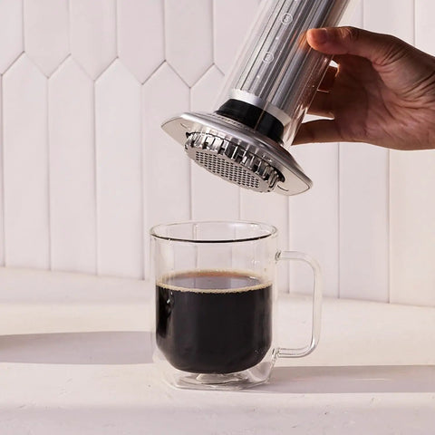 Using the All In One Coffee Press With Glass Chamber, Stainless Steel And Aluminum Build, French Press Pour Over And Espresso Style Manual Brewer, 2 Minute Brew For Rich Flavor And Less Bitterness, Silver to brew coffee into a glass mug.