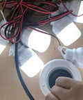 Hand holding 40W Brushless DC Motor With Dual Purpose Micro Gen Reversible Power Output 310V Ball Bearing System beside LED bulbs