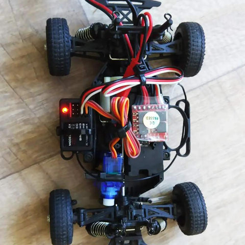 Top-down view of RC car chassis with SG90 micro servo kit, red/white wiring, blue motor, black frame