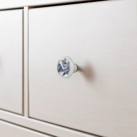Slick One Point Three Seven Inch Marble Look Cabinet Knobs Four Pack Sharp White Cabochon Glass Drawer Pulls With Silver Silk Texture on light drawer.