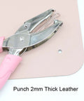 Mini One Quarter Inch Circle Hole Punch With Pink Soft Grip punching 2mm thick leather, shown in use, durable metal build.
