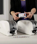 Smart-31 Simplex Id Card Printer Bundle With No Sweat Ezload Kit And Windows Software Includes Two Hundred Fifty Ymcko Ribbon Plus One Hundred Top Shelf Pvc Cards Straight Out The Box with a hand holding a printed ID card.