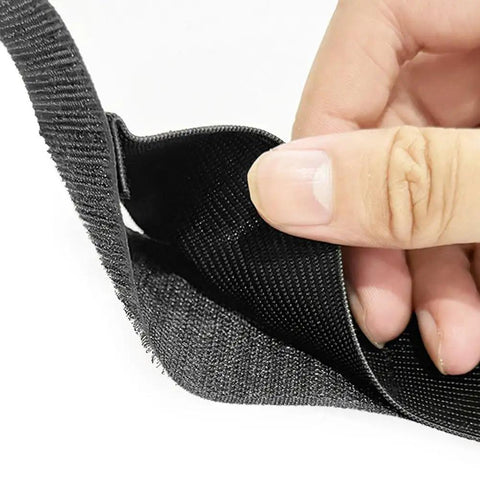 Close-up of hand holding Heavy Duty Car Trunk Organizer Straps with hook and loop tape and reinforced nylon webbing.