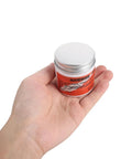 Hand holding a 3.53oz jar of All In One Conductive Grease for Electronics and Woodwinds, 3.53oz White Paste Delivers Stable Conductivity, Safe on Nickel, Brass, and Gold Connectors, Keeps Wind Instrument Switches Smooth and Refurbishes Worn Parts.