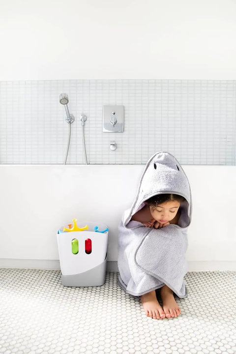 Child in gray towel next to Freestanding Bath Toy Drying Bin With Quick Drain Base, real no mess game changer for keeping kids toys snappy and mold free.