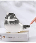 Glass Weather Forecaster Desktop Weather Station Barometer Gift For Women Girlfriend Christmas Birthday Valentine Gift For Her shown as a bird-shaped glass on a book with a hand pointing.