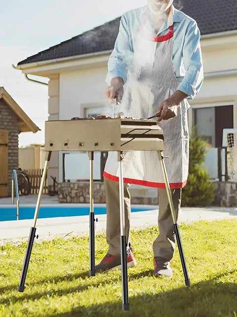 Four Piece Top Tier Folding Table Leg Extenders With Adjustable Heights From Three To Thirteen Inches Crafted From Solid Rust Proof Steel To Elevate Your Setup Kick Lower Back Strain Away And Keep Your Gear Dope For Indoor Or Outdoor Use Daily in use during outdoor grilling.