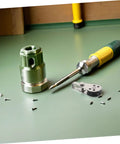 Assorted tools and screws on a green surface, including a screwdriver and metal fittings.