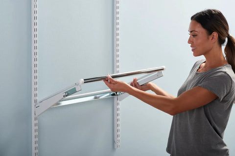 Person installing white sliding basket for closet organization, sturdy pull out wire drawer, adding drawer space in closet system.