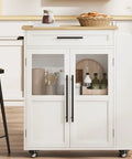 Farmhouse Mobile Kitchen Island Cart With Slick Rolling Lockable Casters And Front Glass Cabinet Plus Roomy Gear Hauler Drawer And Three Tier Spice Shelf For Weekend Cookoffs, white and wood design with glass cabinet.