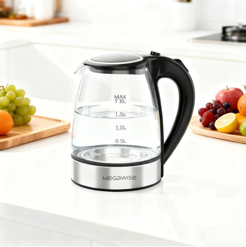 Electric Glass Kettle With Auto Shut Off 1.8L Borosilicate Glass Body Stainless Steel Inner Lid And Base No Plastic Touching Boiling Water Quick Boil Safe Pour Modern Countertop Tea And Coffee Kettle on a kitchen counter with fruits nearby.