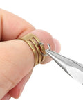 Hand using pliers from 7 Piece Jewelry Pliers Set For Beading And Wire Wrapping on brass rings for jewelry making.