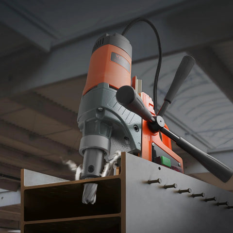 Angled front view of VEVOR magnetic drill press with orange/gray body, drilling into metal beam