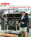 Waterjet intensifier pump with check valve body on an industrial machine; factory setting with worker in hard hat nearby