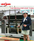 Person demonstrating industrial pump system in factory setting with overhead lifting equipment.