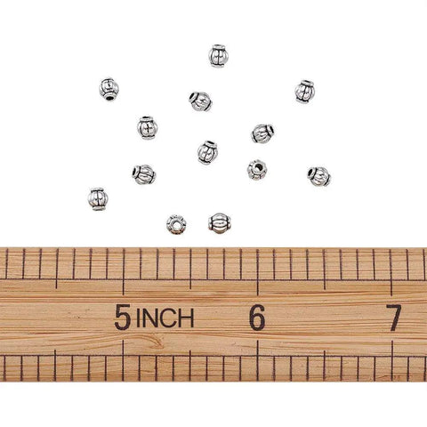 Antique Silver Tibetan Style Pumpkin Spacer Beads 4mm, 100 Piece Set for DIY Jewelry Making shown next to ruler for size comparison.