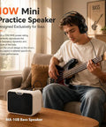 Person playing bass guitar with Compact 10W Bass Amp For Practice, Dual Channel Normal And Drive, next to them on a table.