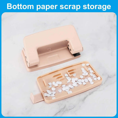 Bottom view of a pink heavy duty hole punch with detachable scrap tray and paper confetti, part of a two-piece metal set for crafts.