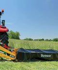 Tractor with Vermeer M7050 mower cutting a field under blue skies, showcasing agricultural equipment in action.