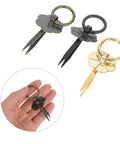 Three vintage round metal drawer pulls with integrated scissors design in gold and black, shown close-up in hand.