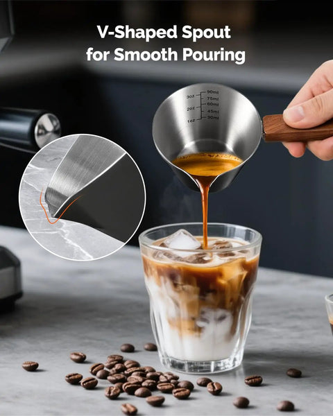Stainless Steel Espresso Measuring Cup With Wide Mouth And V Shaped Pour Spout, Easy Grip Handle, Built In Scale For Latte Cappuccino Americano Macchiato, Pro Grade For Home Baristas Black pouring espresso into iced coffee.
