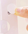 Applying a Self-Adhesive Screw Hole Stickers 15mm White, 96 Count Per Sheet to cover a screw on white furniture surface.