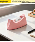 Pink Heavy Duty One Handed Weighted Office Tape Dispenser For 1 Inch Core Pink Grab And Go Quick Reload on white desk