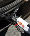 White boat trailer surge brake actuator with orange lockout lever mounted to hitch