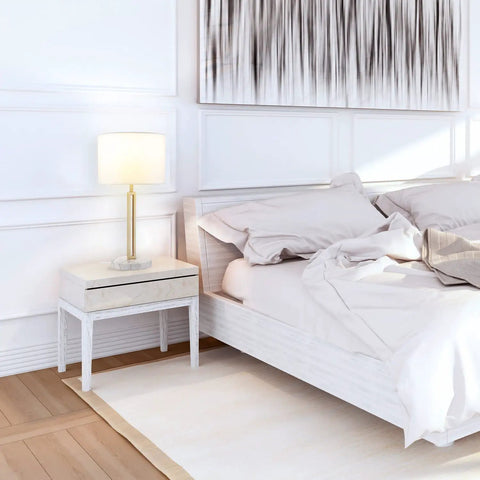 Paloma Table Lamp By Novogratz X Globe in bedroom, on nightstand with white bedding, modern glam cutout body and white fabric shade