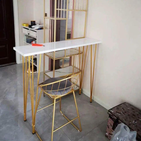 Rock Solid X Frame Steel Pipe Table Legs For Coffee Tables And Bars support a sleek white counter and golden chair in a modern setting.