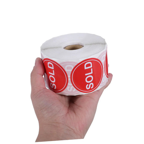 Hand holding roll of Red Round Self Adhesive Sold Stickers Two Inch Paper Labels For Retail Store And Warehouse Inventory Control Pricing Supplies 500 Pack With Strong Adhesion And Uniform Appearance For Clear Tagging And Easy Price Updates