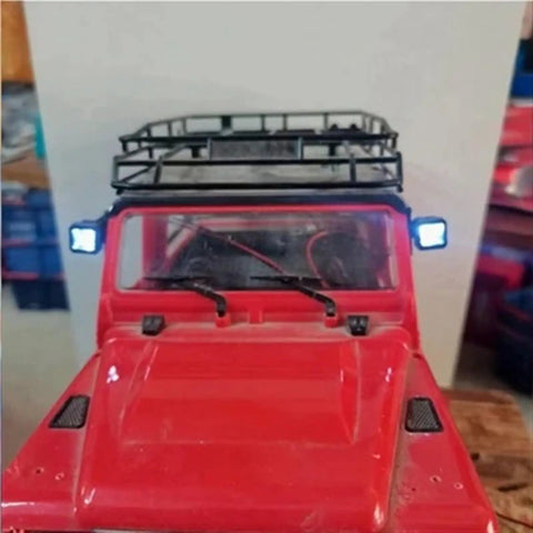 Red RC crawler with Durable RC Light Strips Kit For One Tenth Scale Crawlers Like AXIAL SCX10 90046 with headlights on.