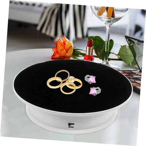 Rotating Electric Turntable Display Stand With Smooth Motorized Motion showcasing gold rings and earrings on a black surface.