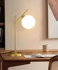 Mid Century Modern Table Lamp With Brass Metal Body And Milky White Glass Globe Shade 1 Light Bedside Lamp on wooden desk