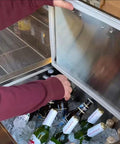 Person using Pro-Level 23X17 Drop-In Stainless Steel Ice Chest With Rock-Solid Dual-Wall Insulation to access beverages.