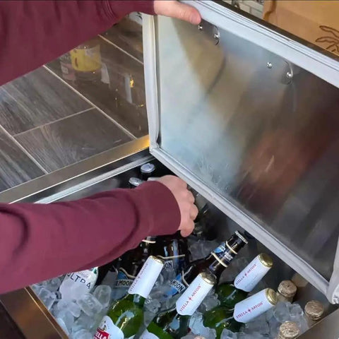 Person using Pro-Level 23X17 Drop-In Stainless Steel Ice Chest With Rock-Solid Dual-Wall Insulation to access beverages.