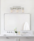 Three Light Brushed Nickel Bathroom Vanity Light Fixture With Clear Glass Shade Over Mirror in modern bathroom setting.