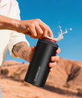 Person using 3 In 1 Slim Can Cooler For 12 Oz Skinny Cans Regular Cans And Beer Bottles Keeps Drinks Cold Up To 6 Hours With Double Walled Stainless Steel Vacuum Insulation No Sweat Matte Black Finish outdoors.