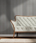 Straight Up Gorgeous Beige Stripe Wallpaper With A Sleek Neutral Silver Metallic Sheen And Cozy Fibrous Texture For That Perfect Modern Lounge Vibe Eco Friendly Pvc Free Wallcovering behind a tufted cream sofa.