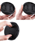 Two-Pack 49mm Front Lens Cap With Keeper For Canon R100 R50 R10, illustrated in hand, showcasing center-pinch design.