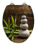 Elongated white zen balance stones bamboo plant wooden table Toilet Seat with stacked stones and green bamboo leaves.