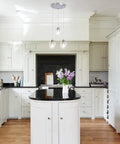 Three Light Pendant Lighting With Clear Glass And Adjustable Silver Cord In Brushed Nickel installed over kitchen island
