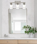 Three Light Wall Mount Bathroom Light Fixture In Brushed Nickel Finish With Seeded Glass Shade above mirror