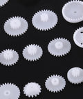 Grab This Awesome DIY Robot Gears And Pulley Belt Kit With 64 Kinds Of Wearable Plastic Parts Perfect For Tech Models, Car Robots, And Cool Motor Projects You Can Build Your Own Stuff With Today. white plastic gears on black background