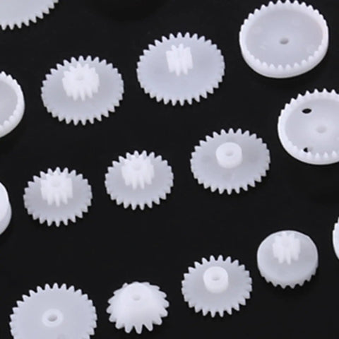 Grab This Awesome DIY Robot Gears And Pulley Belt Kit With 64 Kinds Of Wearable Plastic Parts Perfect For Tech Models, Car Robots, And Cool Motor Projects You Can Build Your Own Stuff With Today. white plastic gears on black background